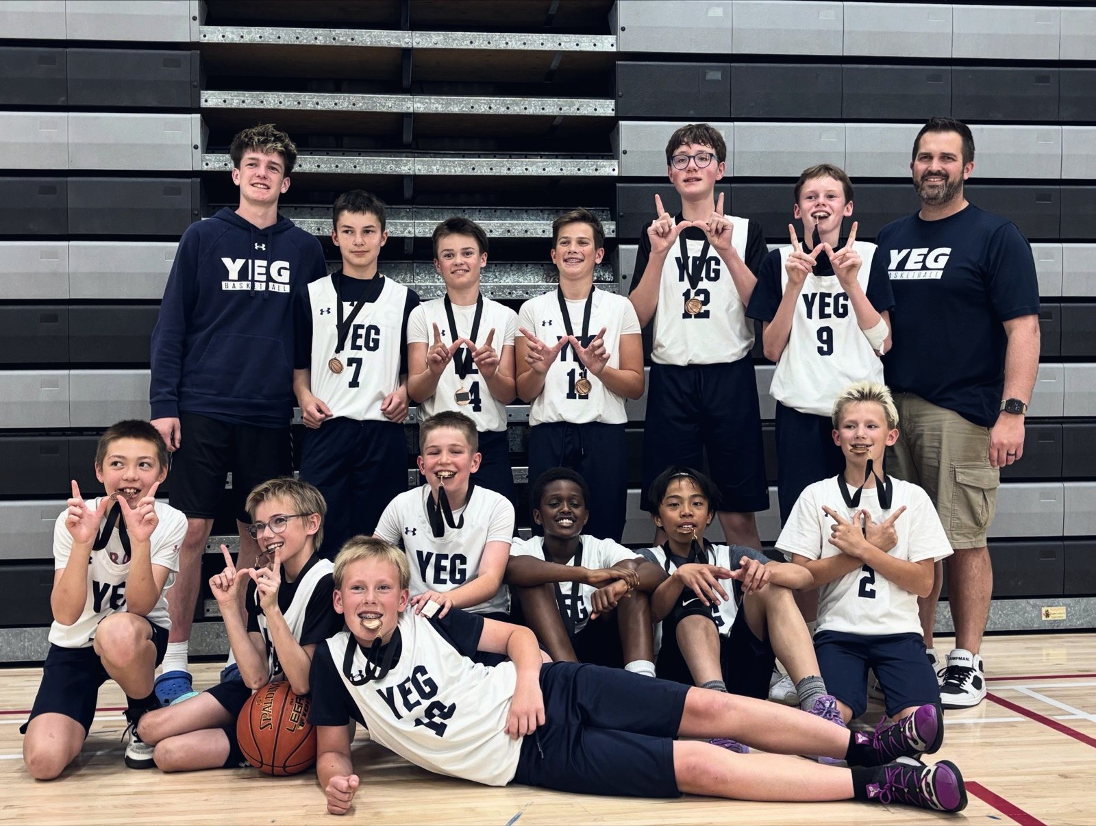 A YEG BASKETBALL boys team with medals and their coach